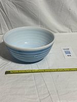 Top angled view of Pyrex 403 blue striped bowl with measuring tape for scale