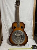 Front view showing sunburst body, resonator cover, missing strings