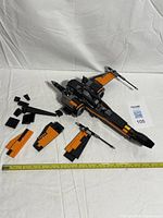 Partially assembled Lego Poe's X-Wing Fighter with measuring tape