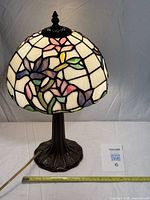Full view of illuminated stained-glass table lamp showing shade pattern and metal base