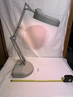 Full view of gray Luxo articulating magnifier lamp with measuring tape for scale