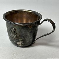 Side view of cup showing duck motif, handle and patina