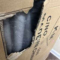 Torn section of box showing black item inside