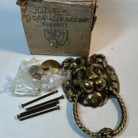 Front view of lion head door knocker, mounting hardware and box