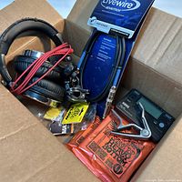Full lot in box showing headphones, cable, capo, picks, strings, tuner