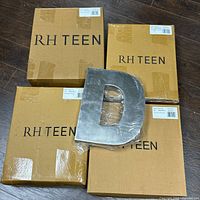 Three boxed RH Teen metal letters and one loose letter D on wooden floor