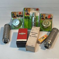 Full view of all eight engine parts including carded mufflers, loose baffles, boxed items and spark plug