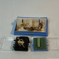 Overview of the four gold-tone accessories inside cases