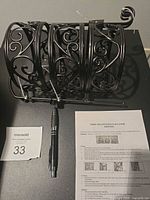 All three black metal stands stacked together with instruction sheet and pen for scale