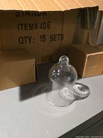 single clear glass dome ornament in front of outer carton