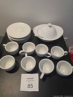 Full set showing stack of saucers, group of eight cups, and covered serving dish