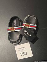 Top view of Gucci baby shoes showing strap, logo hardware and size tag