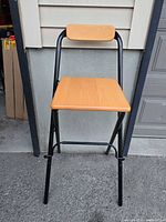 Front view of folding bar stool showing seat, backrest and frame