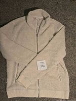 Full view of Frank And Oak cream sherpa fleece jacket laid flat