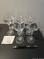 Front angle of eight clear stemmed glasses grouped together