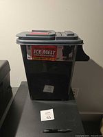 Full view of grey plastic ice melt dispenser on table