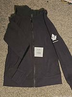 Full view of black Lululemon hoodie laid flat, zipper closed