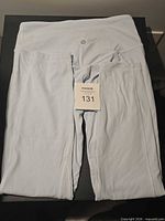 Front view of folded light blue leggings showing waistband and logo