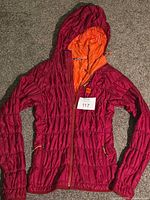 Full view of magenta MEC hooded jacket laid flat