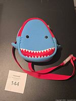 Front view of blue shark-shaped backpack with red strap