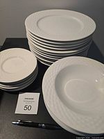 Stacked dinner plates, side plates, and bowls with reference pen and lot card