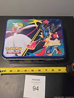 Front view of Pokémon metal lunch tin showing graphics and size reference tape measure