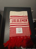 Folded cream and red Lululemon scarf showing brand name and tassel fringe