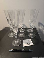 front view of seven clear champagne flutes on table