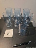 seven light blue stemmed glasses grouped on table