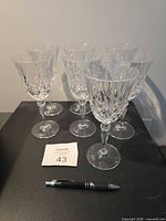Seven cut crystal wine glasses front view with pen for scale