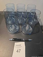 eight blue tinted tumblers arranged on table