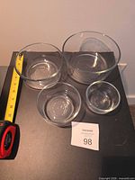 All four clear glass bowls nested with tape measure for scale
