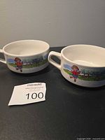 Two white ceramic handled bowls with illustrated band