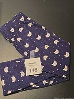 Folded navy leggings with cat face and dot print, lot tag visible