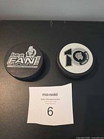 Two Ottawa Senators pucks showing Be A Fan and 10th Anniversary graphics