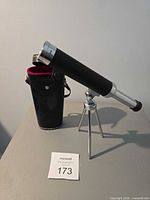 Telescope mounted on tripod beside carrying case