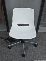 front view of white plastic swivel chair showing seat cut-out and base