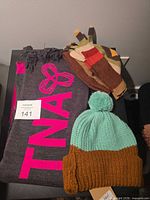 Scarf, beanie and gloves arranged on table