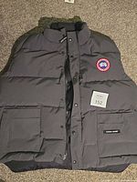 Full view of front of Canada Goose down vest showing overall condition, pockets, zipper and snap closure
