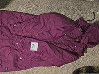 Full view of purple MEC long coat laid flat showing exterior, hood, pockets, closure.