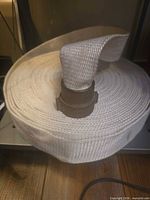 Rolled white cotton canvas fire hose on shelf