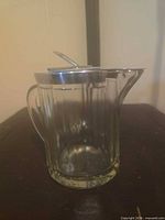 Side view showing ribbed glass body, handle, spout, lid