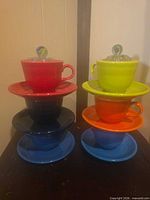 Two stacks of six colorful Fiesta cups and saucers with glass flower frogs on top
