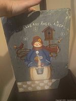 Front view of painted slate plaque with snowman design and text