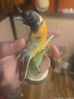 Full left-side view of porcelain bird figurine in hand