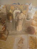 Front view showing both glass perfume bottles, mannequin figurine, glass tray, decorative card, yarn ball