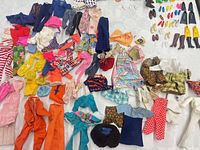 overview of mixed Barbie clothes and accessories spread on table