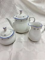 Teapot, sugar bowl with lid, and creamer grouped together showing design