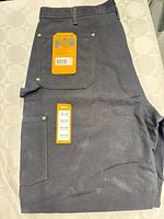 Folded black Carhartt work pants showing front pocket and tags