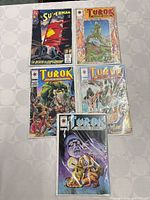 Five comic books on table: Superman #75 and four Turok issues